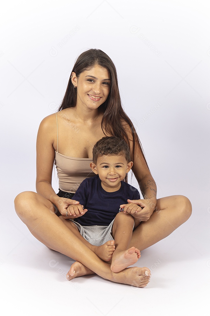 Mãe sentada no chão com filho no colo sobre um fundo branco.