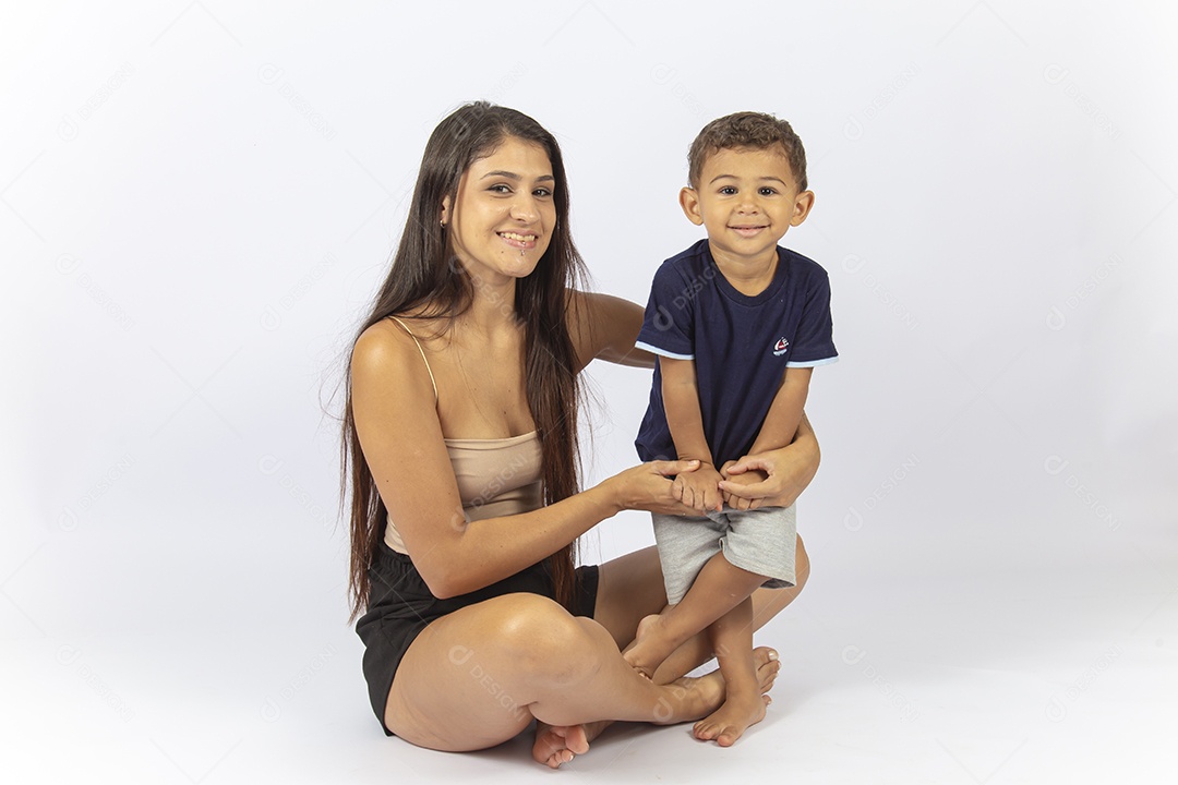 Mãe sentada no chão com filho no colo sobre um fundo branco.