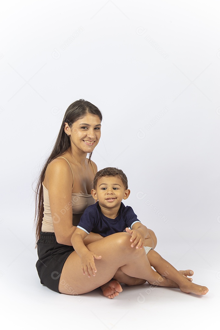 Mãe sentada no chão com filho no colo sobre um fundo branco.