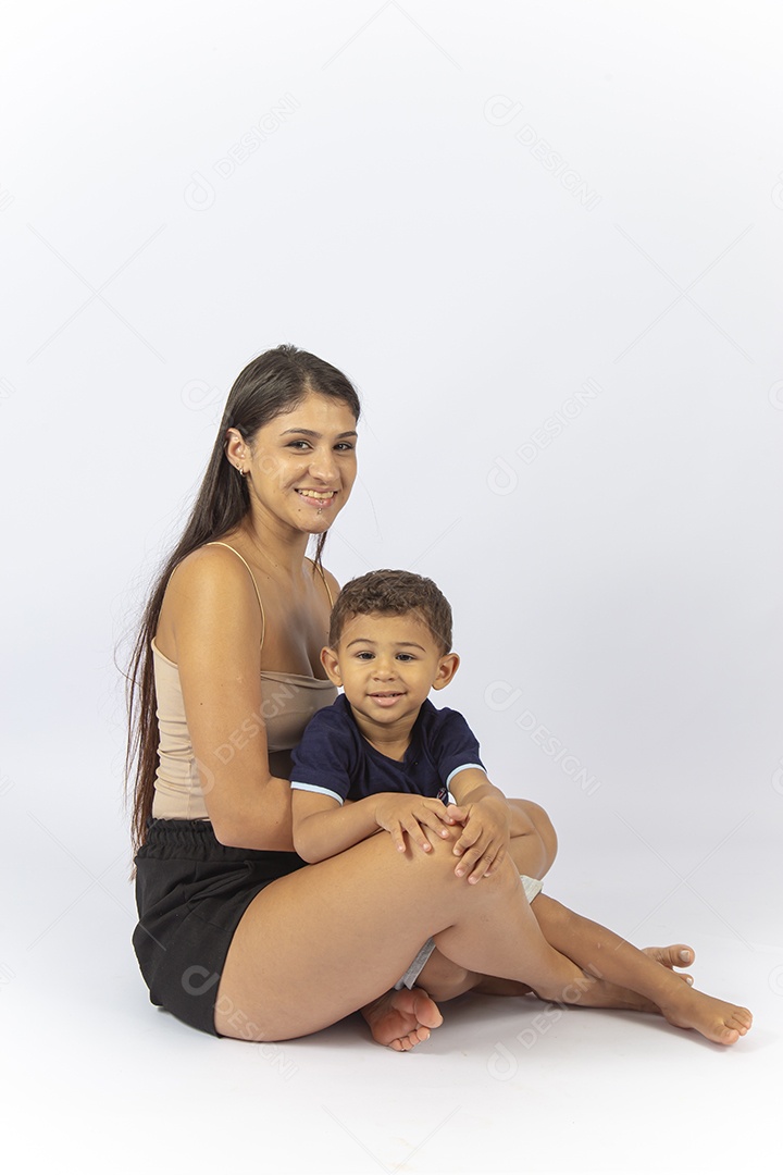 Mãe sentada no chão com filho no colo sobre um fundo branco.