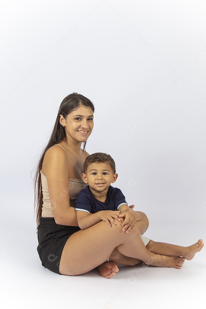 Mãe sentada no chão com filho no colo sobre um fundo branco.