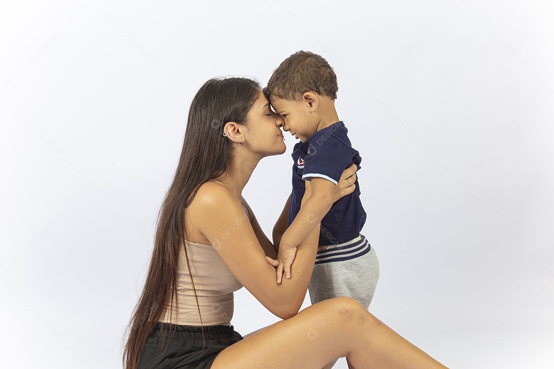 Mãe sentada no chão de frente para o filho sobre um fundo branco.