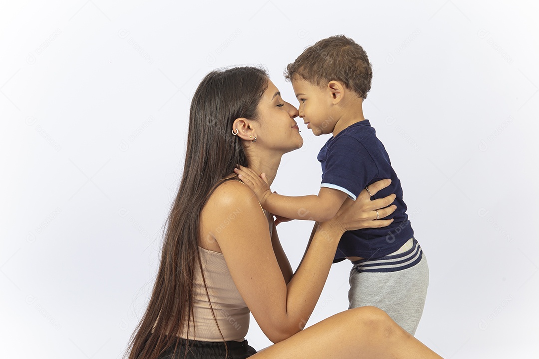 Mãe sentada no chão de frente para o filho sobre um fundo branco.