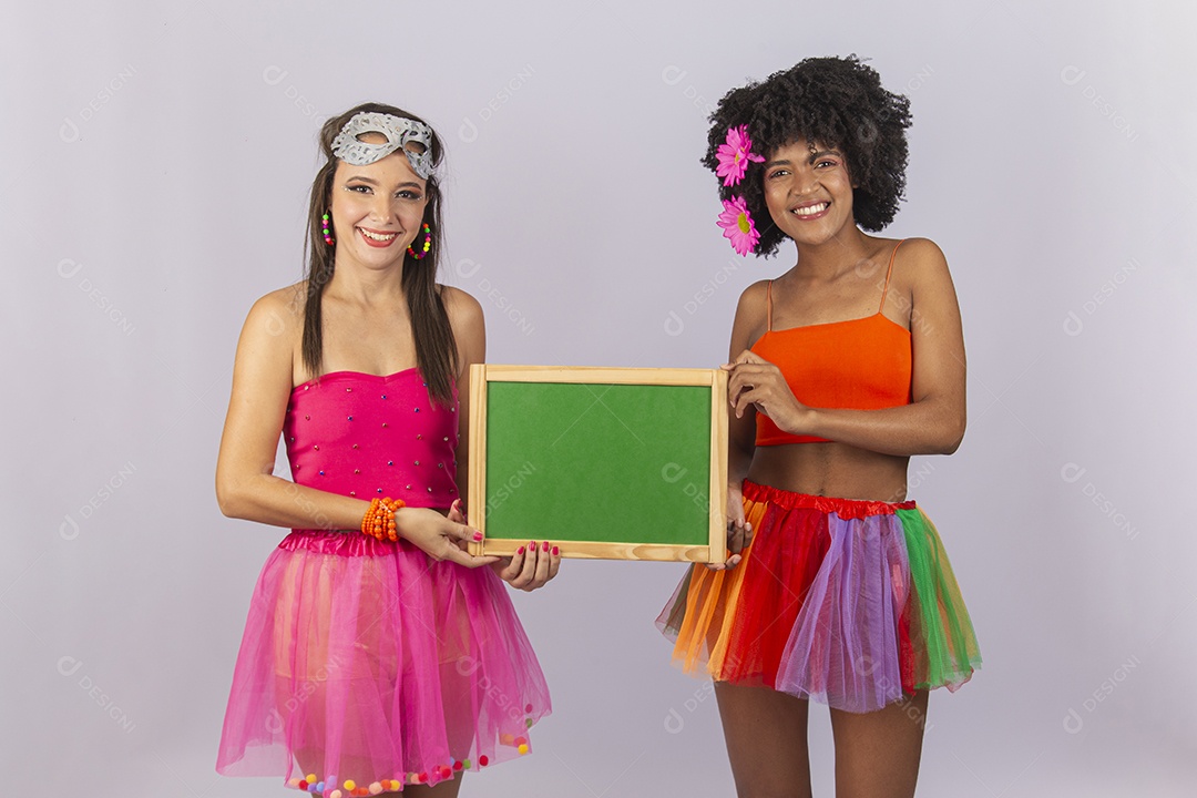 Duas lindas mulheres vestidas com fantasia de carnaval segurando um pequeno quadro.
