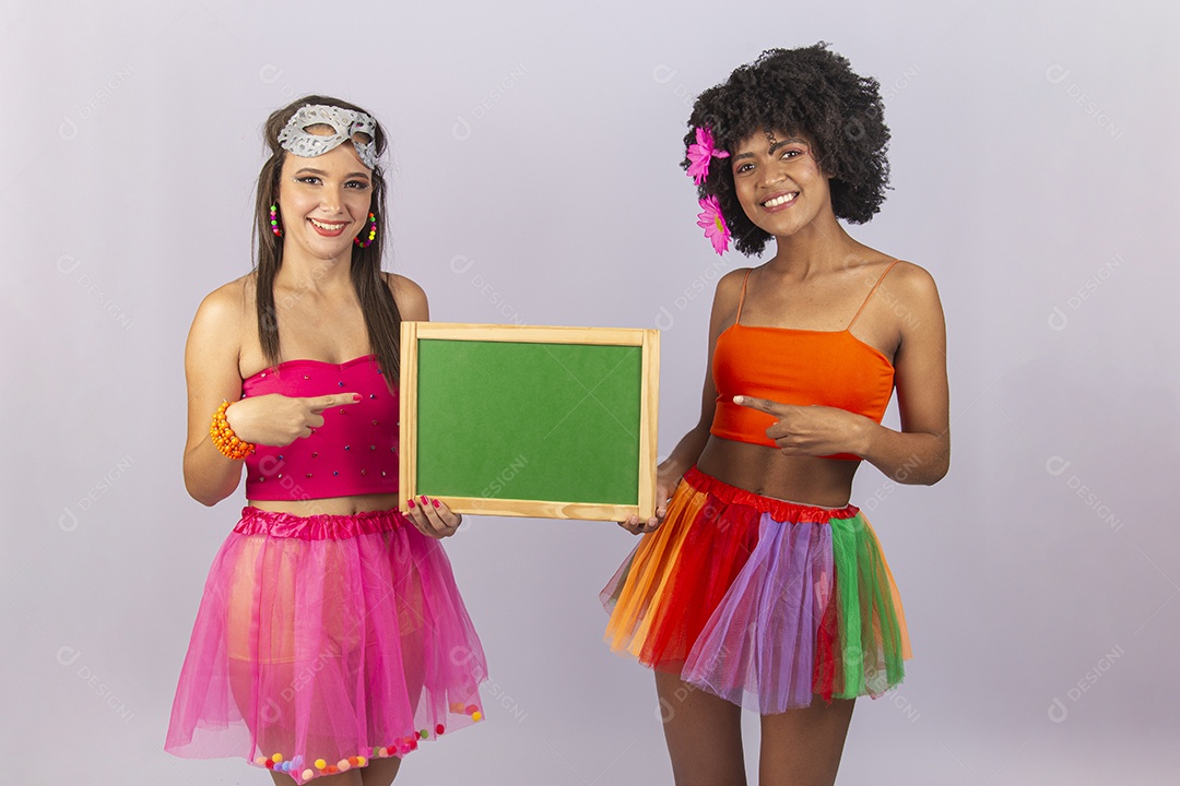 Duas lindas mulheres vestidas com fantasia de carnaval segurando um pequeno quadro.