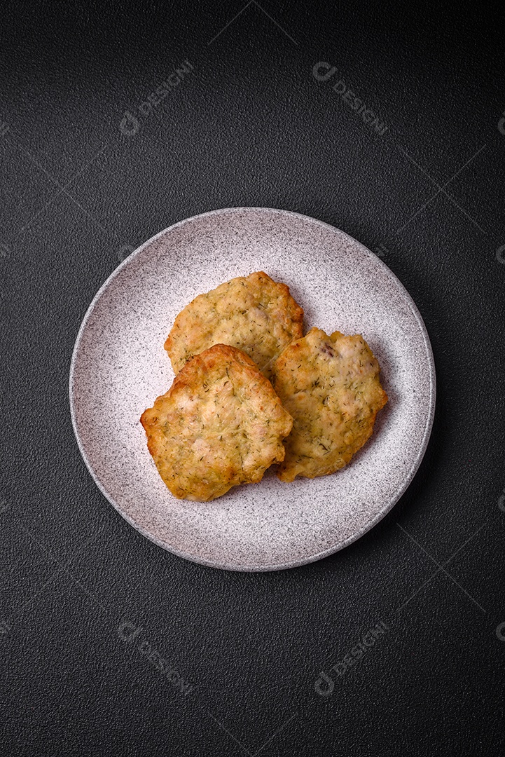 Delicioso frango frito suculento ou panquecas de porco com sal, especiarias e ervas sobre um fundo escuro de concreto