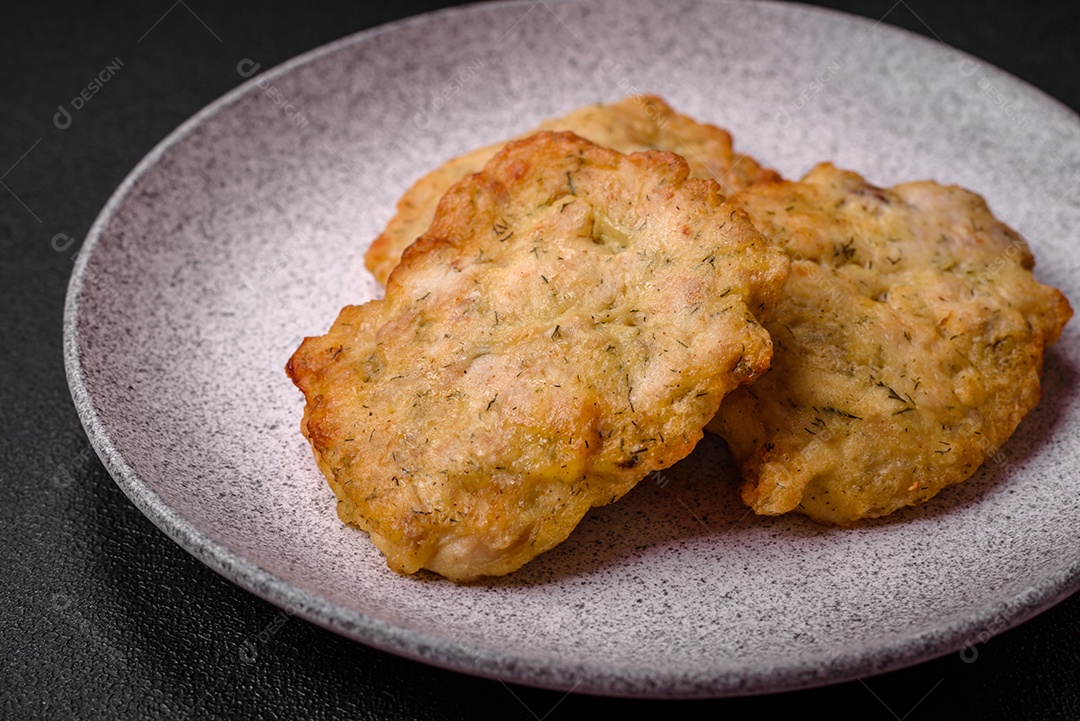 Delicioso frango frito suculento ou panquecas de porco com sal, especiarias e ervas sobre um fundo escuro de concreto