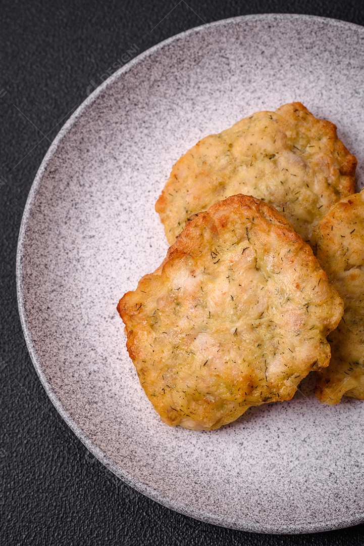 Delicioso frango frito suculento ou panquecas de porco com sal, especiarias e ervas sobre um fundo escuro de concreto