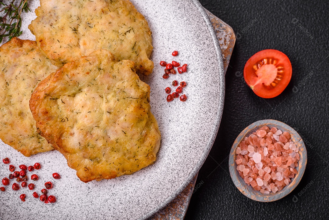 Delicioso frango frito suculento ou panquecas de porco com sal, especiarias e ervas sobre um fundo escuro de concreto