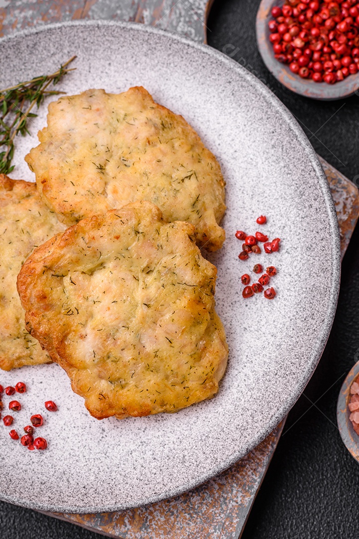 Delicioso frango frito suculento ou panquecas de porco com sal, especiarias e ervas sobre um fundo escuro de concreto