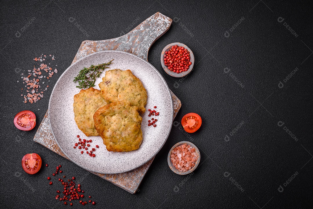 Delicioso frango frito suculento ou panquecas de porco com sal, especiarias e ervas sobre um fundo escuro de concreto