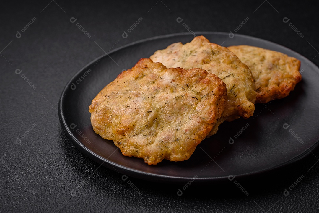 Delicioso frango frito suculento ou panquecas de porco com sal, especiarias e ervas sobre um fundo escuro de concreto