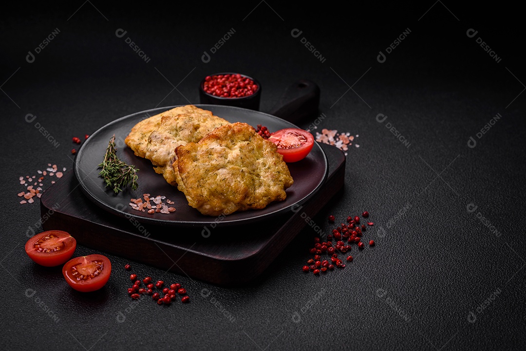 Delicioso frango frito suculento ou panquecas de porco com sal, especiarias e ervas sobre um fundo escuro de concreto