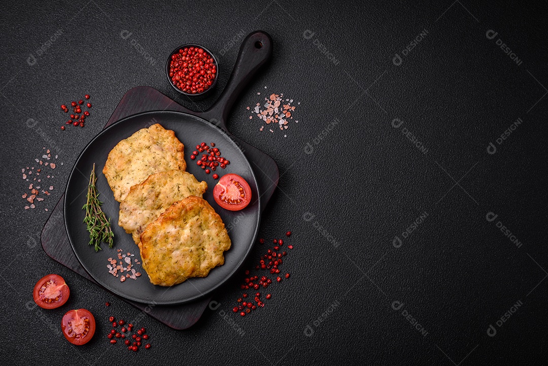 Delicioso frango frito suculento ou panquecas de porco com sal, especiarias e ervas sobre um fundo escuro de concreto