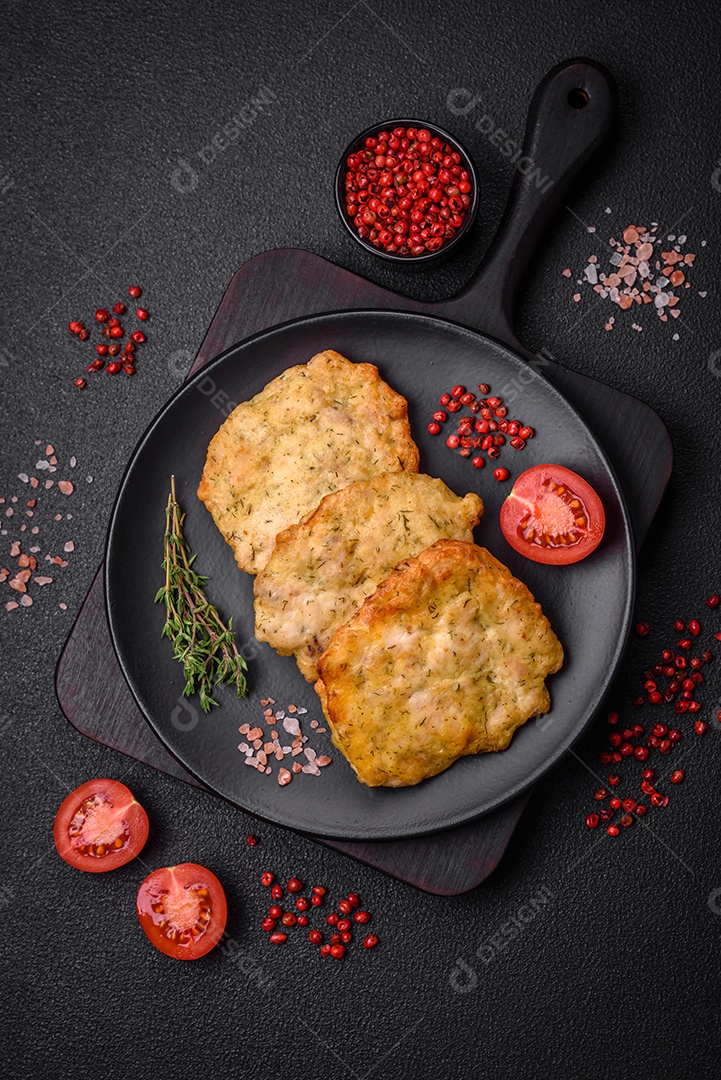 Delicioso frango frito suculento ou panquecas de porco com sal, especiarias e ervas sobre um fundo escuro de concreto