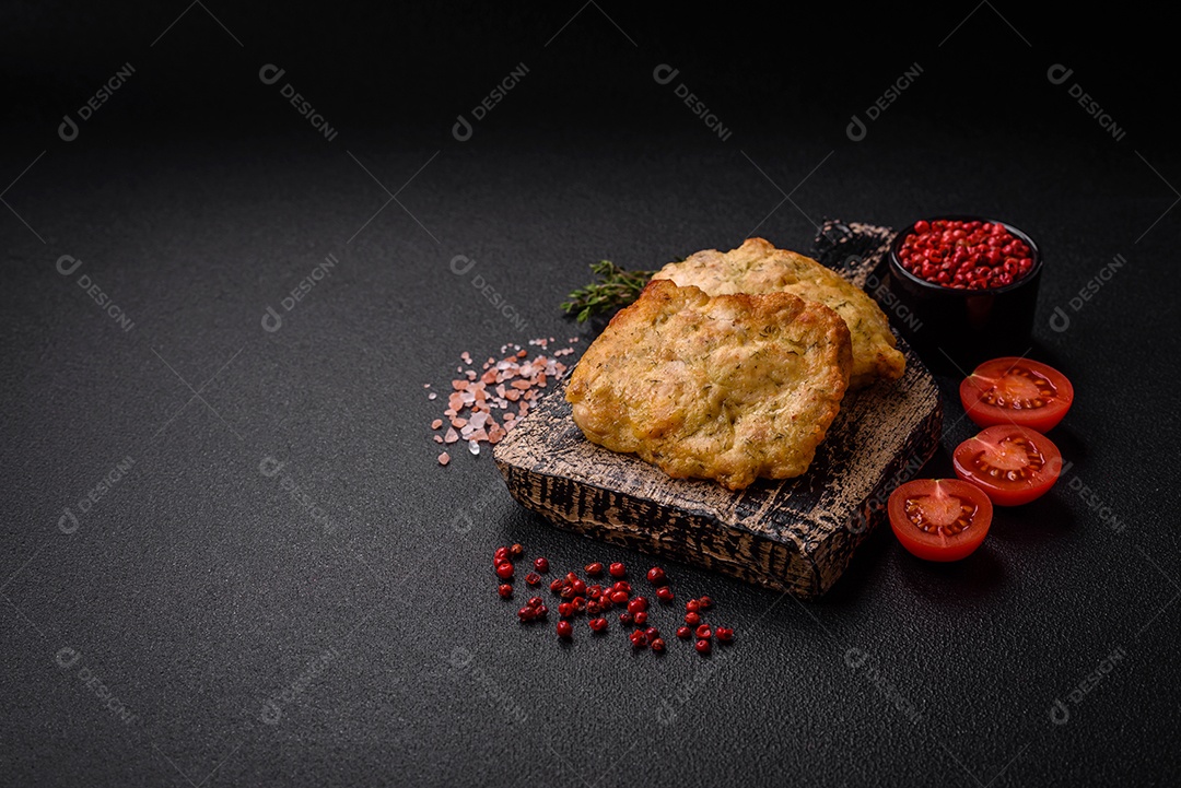 Delicioso frango frito suculento ou panquecas de porco com sal, especiarias e ervas sobre um fundo escuro de concreto