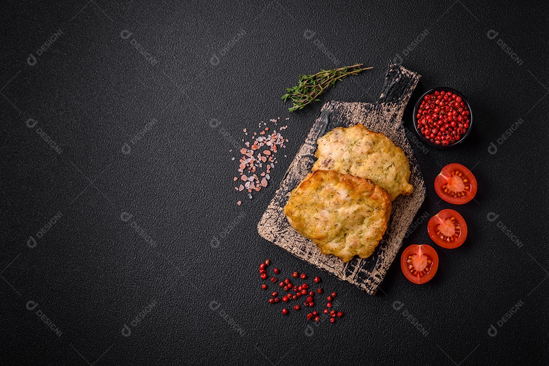 Delicioso frango frito suculento ou panquecas de porco com sal, especiarias e ervas sobre um fundo escuro de concreto
