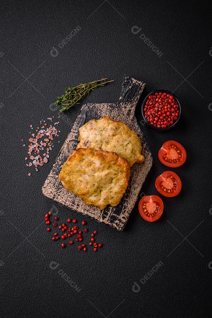 Delicioso frango frito suculento ou panquecas de porco com sal, especiarias e ervas sobre um fundo escuro de concreto
