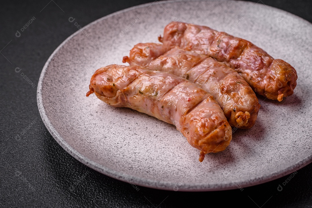 Deliciosos e suculentos enchidos de frango ou porco grelhados com sal, especiarias e ervas sobre um fundo escuro de concreto