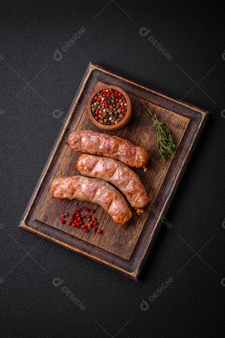 Deliciosos e suculentos enchidos de frango ou porco grelhados com sal, especiarias e ervas sobre um fundo escuro de concreto