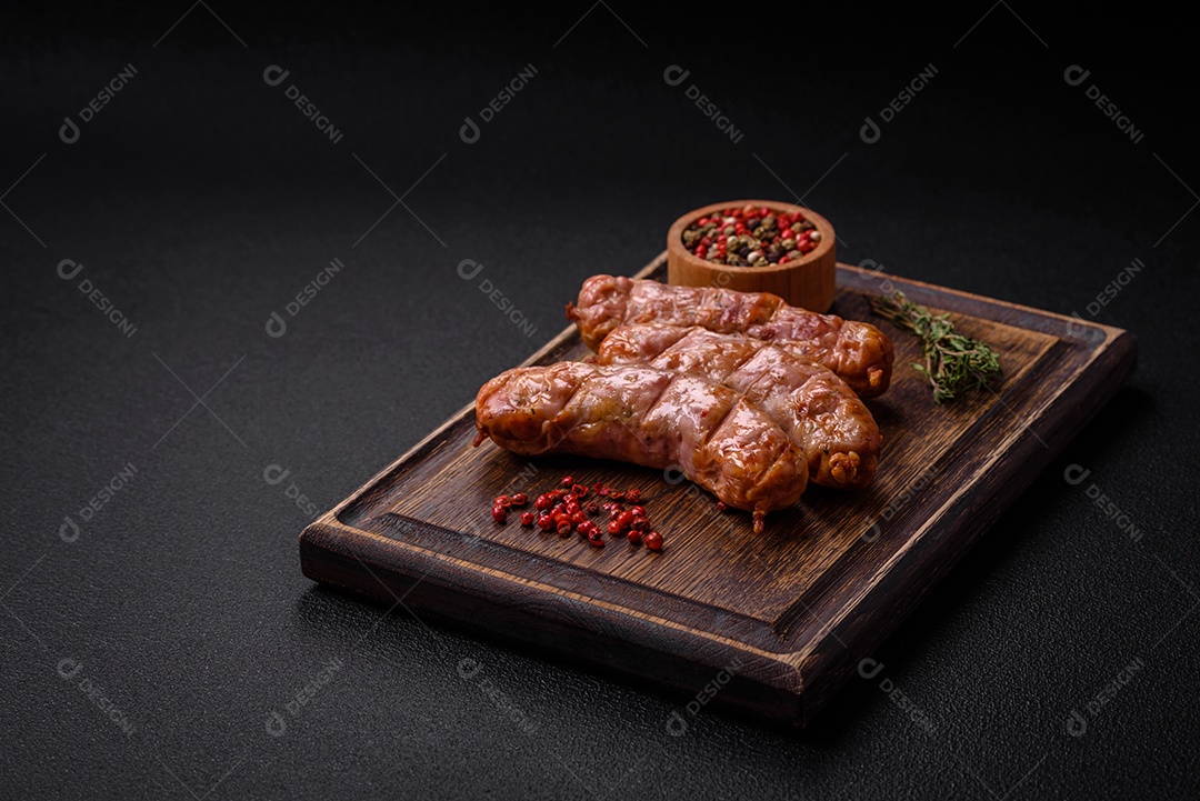 Deliciosos e suculentos enchidos de frango ou porco grelhados com sal, especiarias e ervas sobre um fundo escuro de concreto