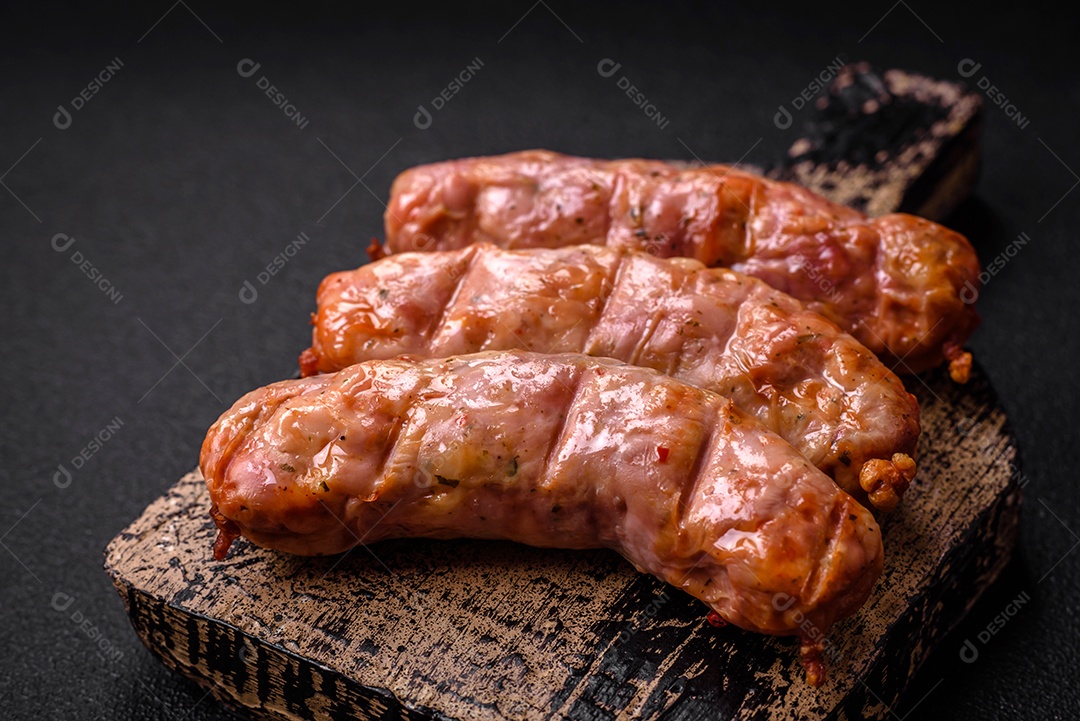 Deliciosos e suculentos enchidos de frango ou porco grelhados com sal, especiarias e ervas sobre um fundo escuro de concreto