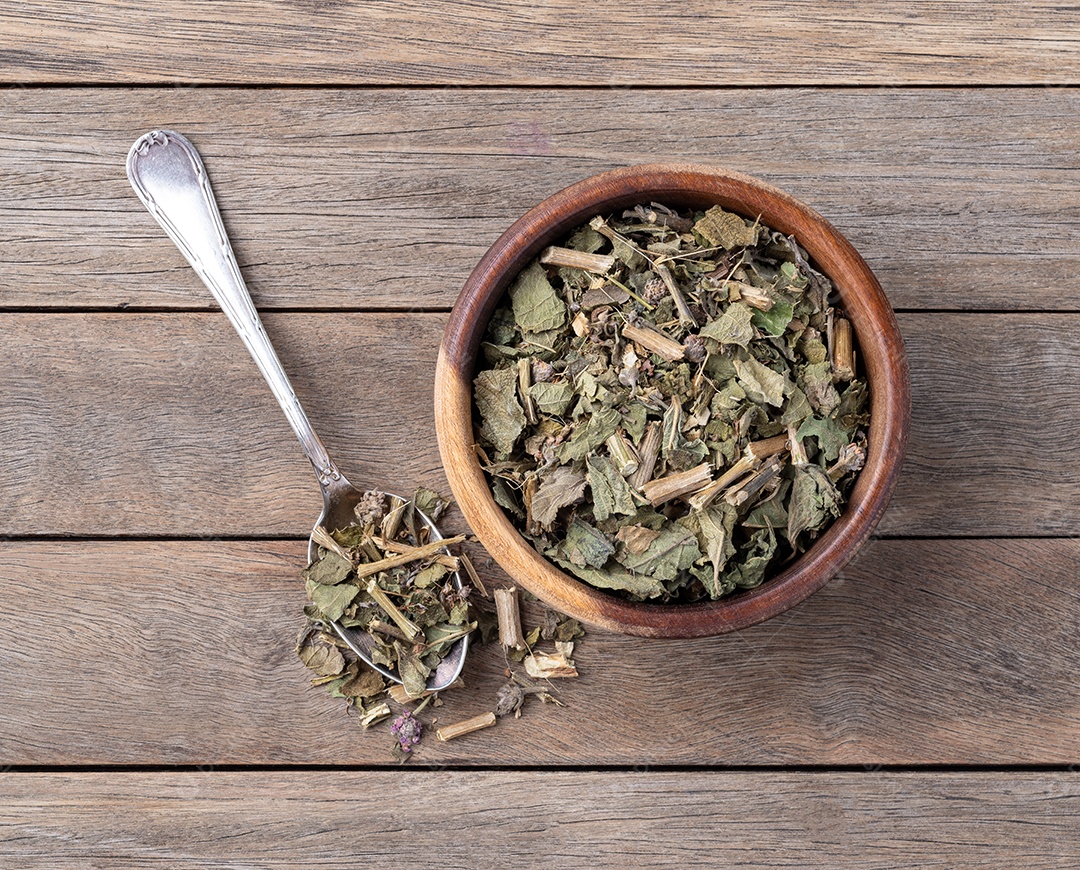 Folhas de erva-cidreira ou Melissa secas em uma tigela e encima de colher