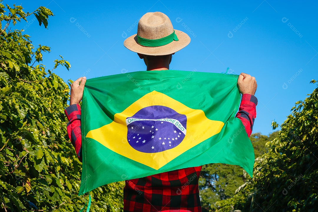 Agricultor em plantação de café segurando uma bandeira brasileira