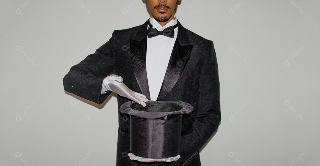 Jovem mágico ilusionista negro fazendo mágica com uma cartola e uma varinha mágica