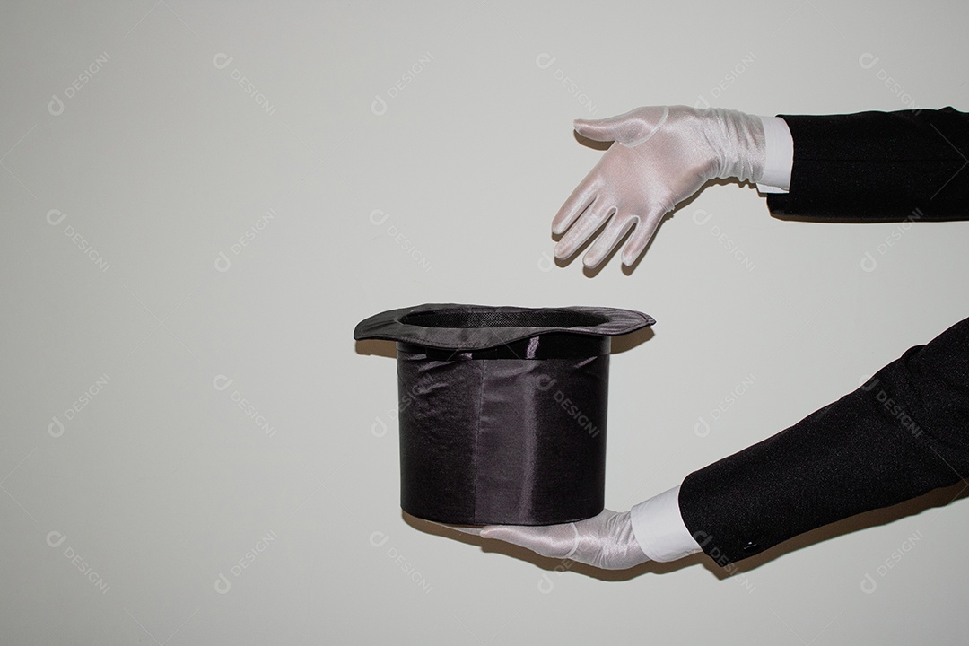 Jovem mágico ilusionista negro fazendo mágica com uma cartola e uma varinha mágica