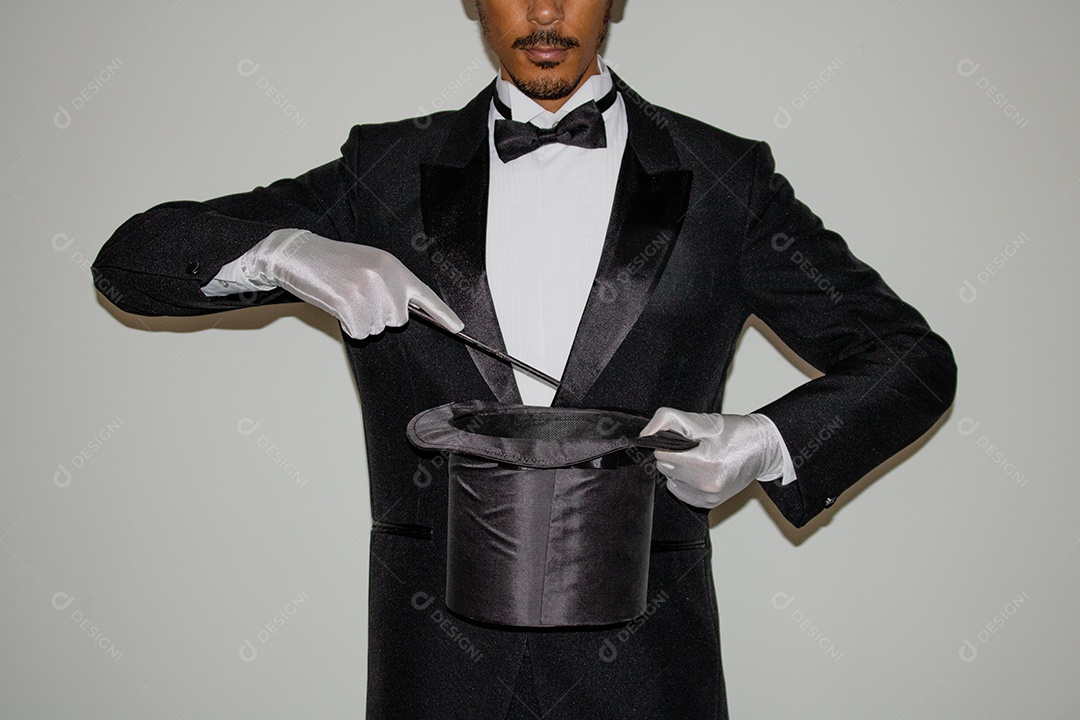 Jovem mágico ilusionista negro fazendo mágica com uma cartola e uma varinha mágica