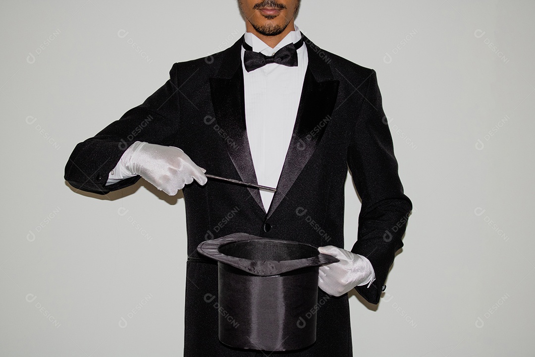 Jovem mágico ilusionista negro fazendo mágica com uma cartola e uma varinha mágica