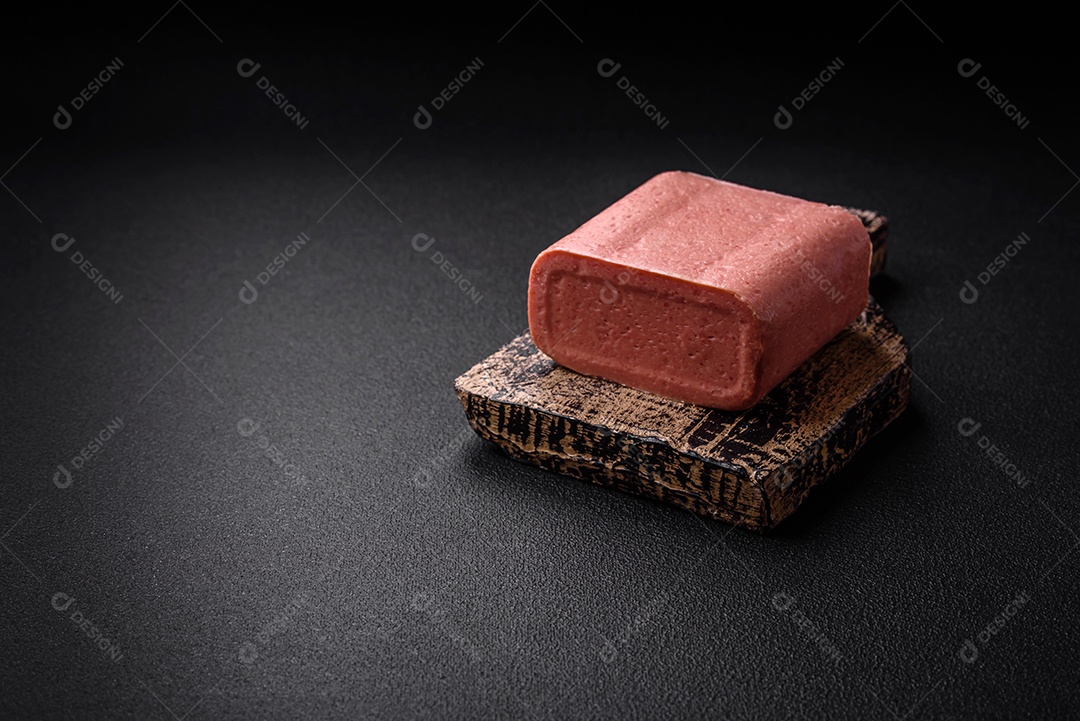 Delicioso presunto rosa enlatado com sal, especiarias e ervas sobre um fundo escuro de concreto