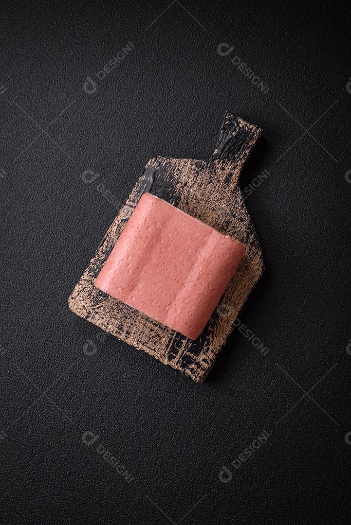 Delicioso presunto rosa enlatado com sal, especiarias e ervas sobre um fundo escuro de concreto