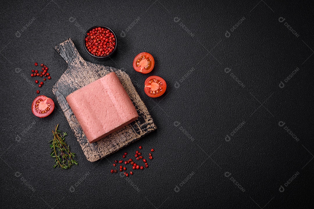 Delicioso presunto rosa enlatado com sal, especiarias e ervas sobre um fundo escuro de concreto