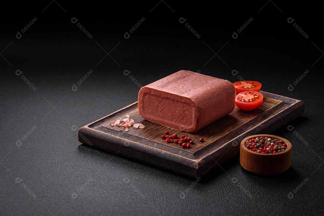 Delicioso presunto rosa enlatado com sal, especiarias e ervas sobre um fundo escuro de concreto