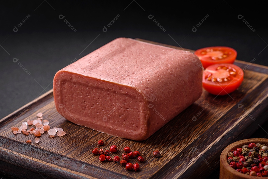 Delicioso presunto rosa enlatado com sal, especiarias e ervas sobre um fundo escuro de concreto