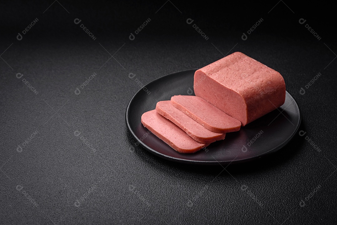Delicioso presunto rosa enlatado com sal, especiarias e ervas sobre um fundo escuro de concreto