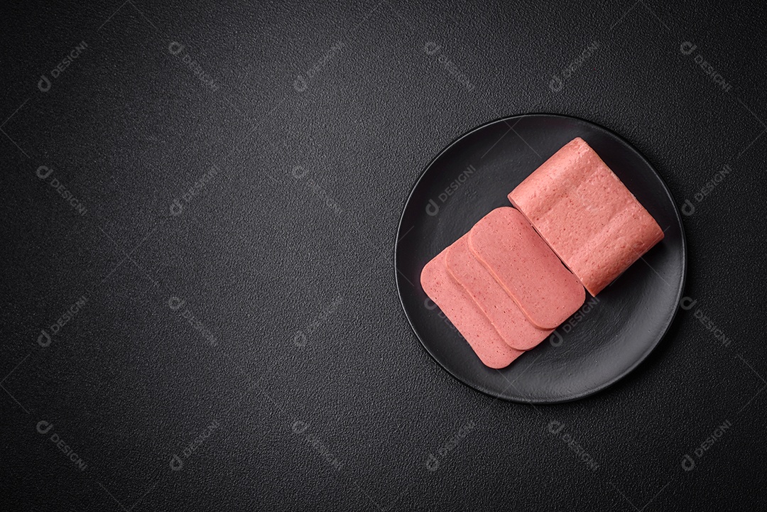 Delicioso presunto rosa enlatado com sal, especiarias e ervas sobre um fundo escuro de concreto