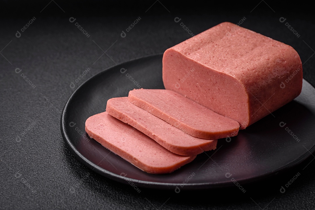 Delicioso presunto rosa enlatado com sal, especiarias e ervas sobre um fundo escuro de concreto