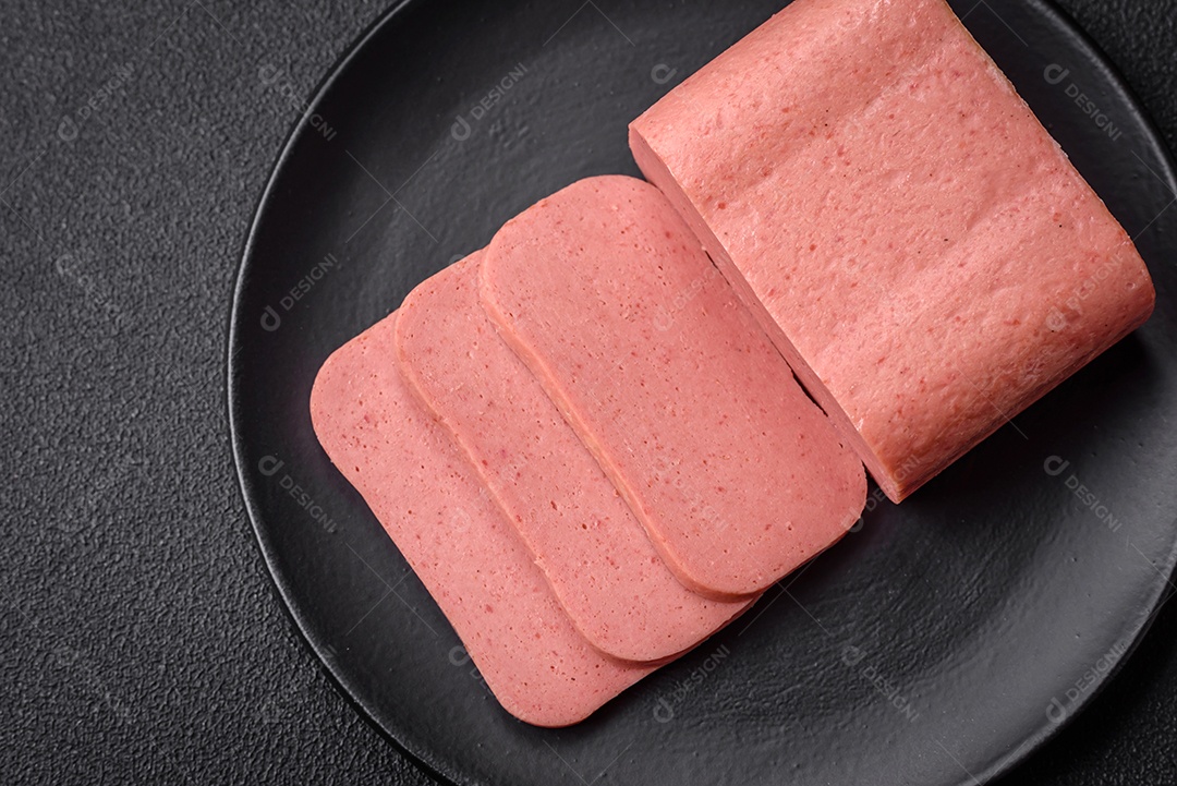 Delicioso presunto rosa enlatado com sal, especiarias e ervas sobre um fundo escuro de concreto