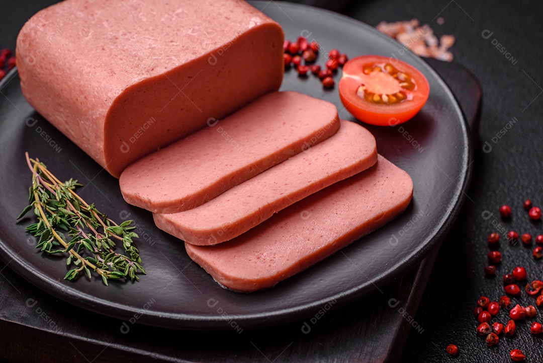 Delicioso presunto rosa enlatado com sal, especiarias e ervas sobre um fundo escuro de concreto