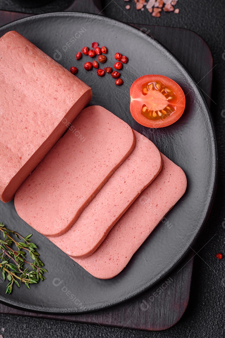 Delicioso presunto rosa enlatado com sal, especiarias e ervas sobre um fundo escuro de concreto