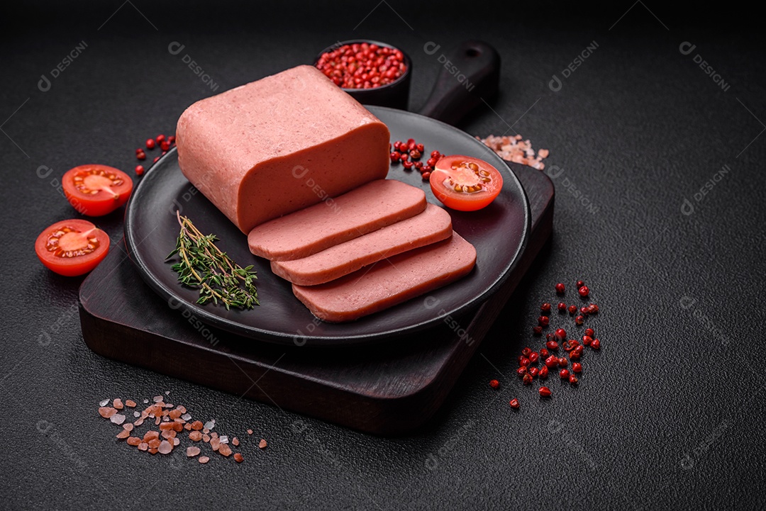 Delicioso presunto rosa enlatado com sal, especiarias e ervas sobre um fundo escuro de concreto