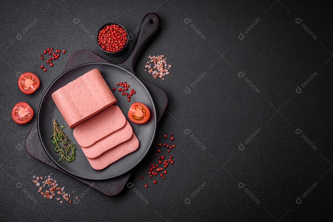 Delicioso presunto rosa enlatado com sal, especiarias e ervas sobre um fundo escuro de concreto