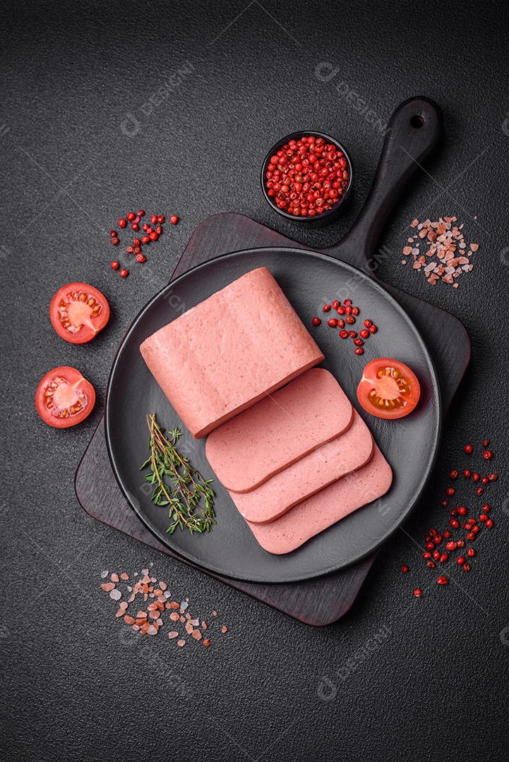 Delicioso presunto rosa enlatado com sal, especiarias e ervas sobre um fundo escuro de concreto