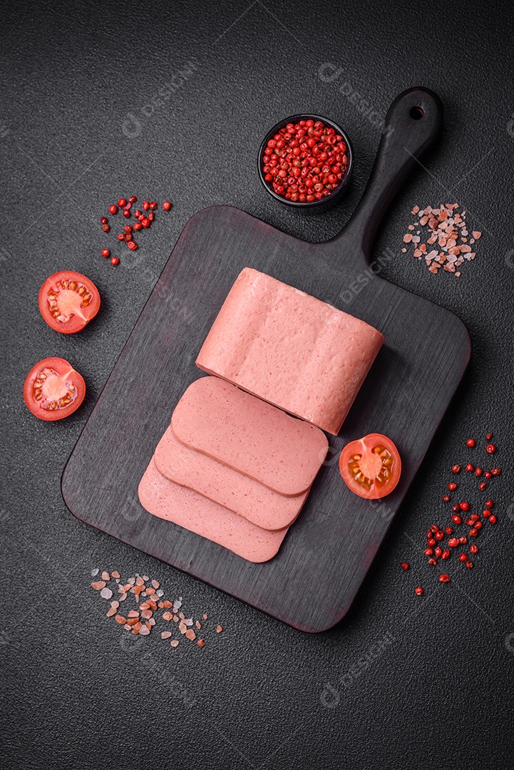 Delicioso presunto rosa enlatado com sal, especiarias e ervas sobre um fundo escuro de concreto