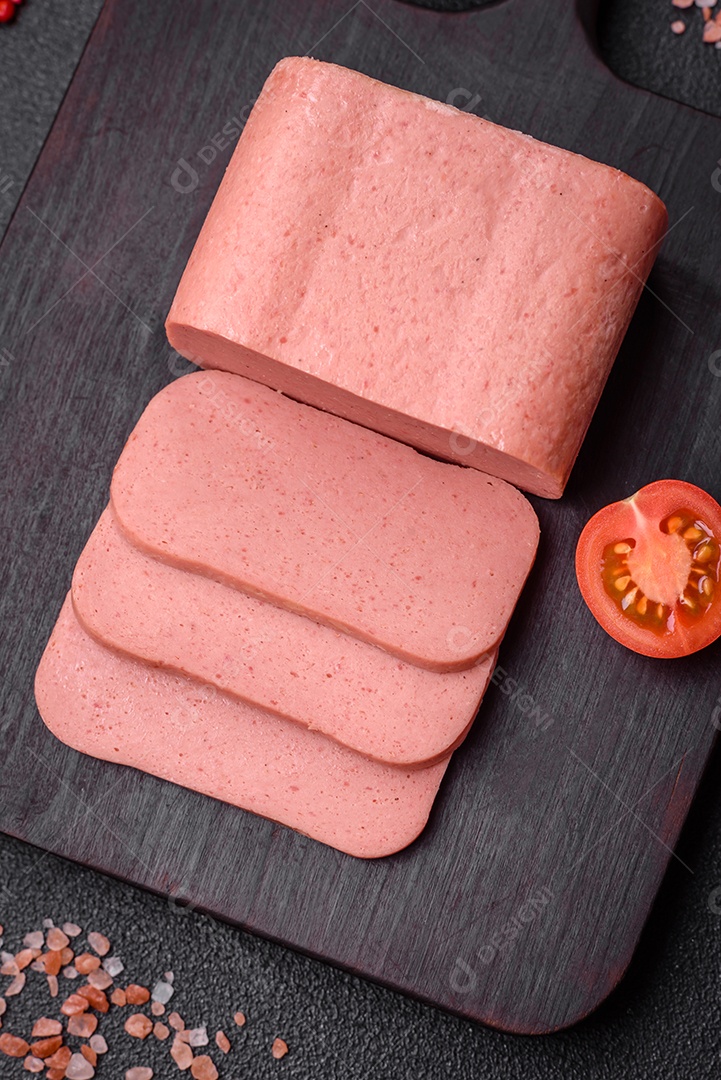 Delicioso presunto rosa enlatado com sal, especiarias e ervas sobre um fundo escuro de concreto