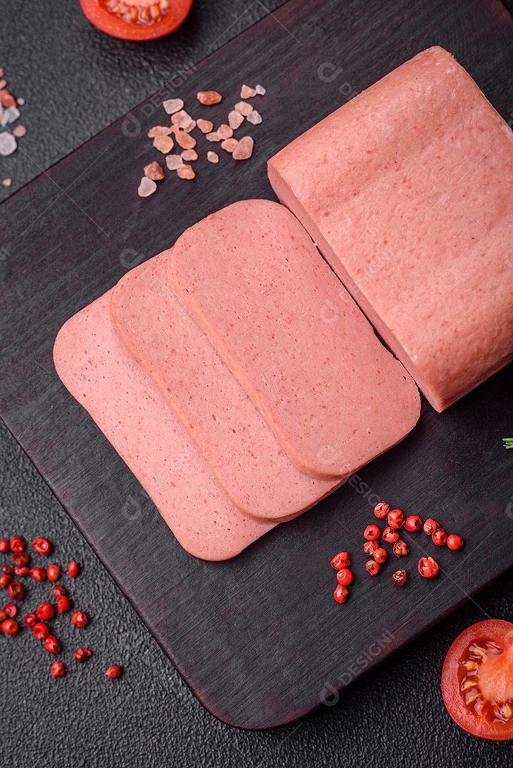 Delicioso presunto rosa enlatado com sal, especiarias e ervas sobre um fundo escuro de concreto