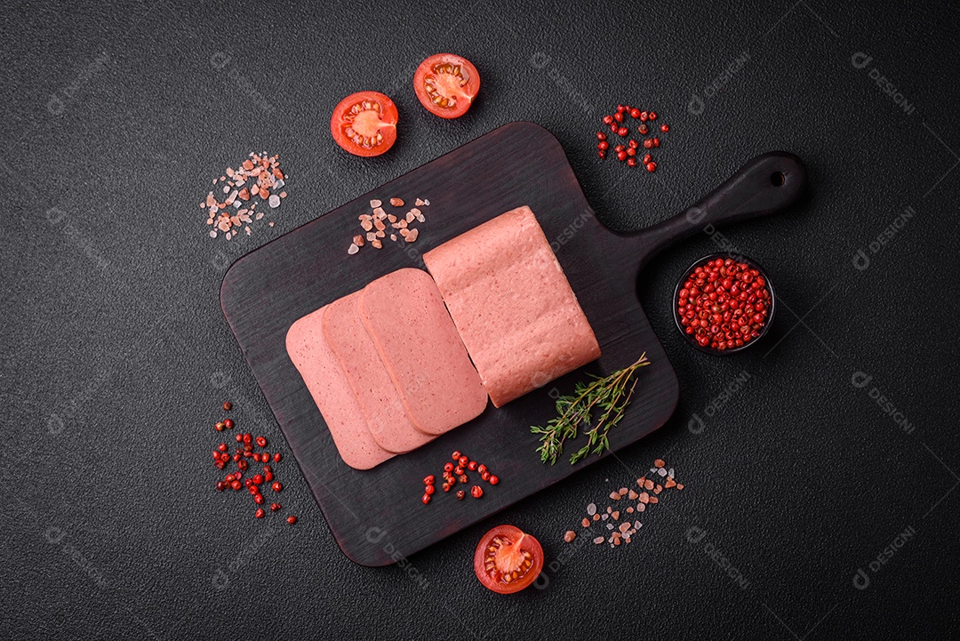 Delicioso presunto rosa enlatado com sal, especiarias e ervas sobre um fundo escuro de concreto